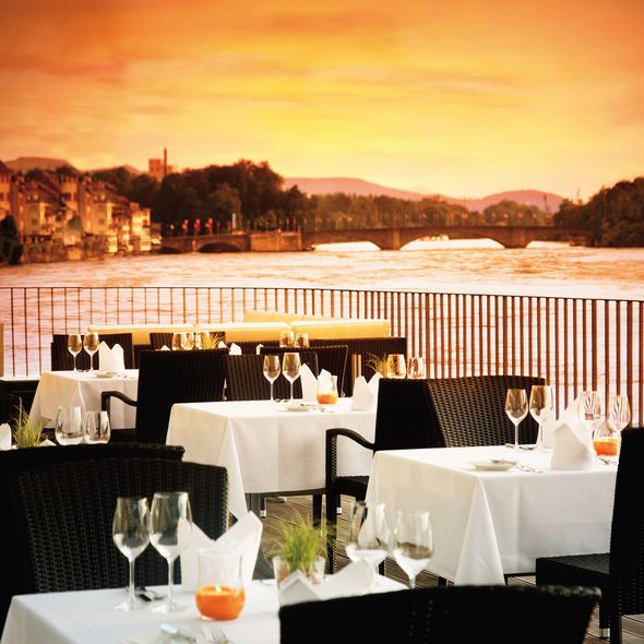 Abendstimmung mit orangem Himmel auf eingedeckter Rheinterrasse ohne Gäste