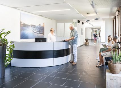 Mitarbeiterin begrüsst Patient am Therapie-Empfang